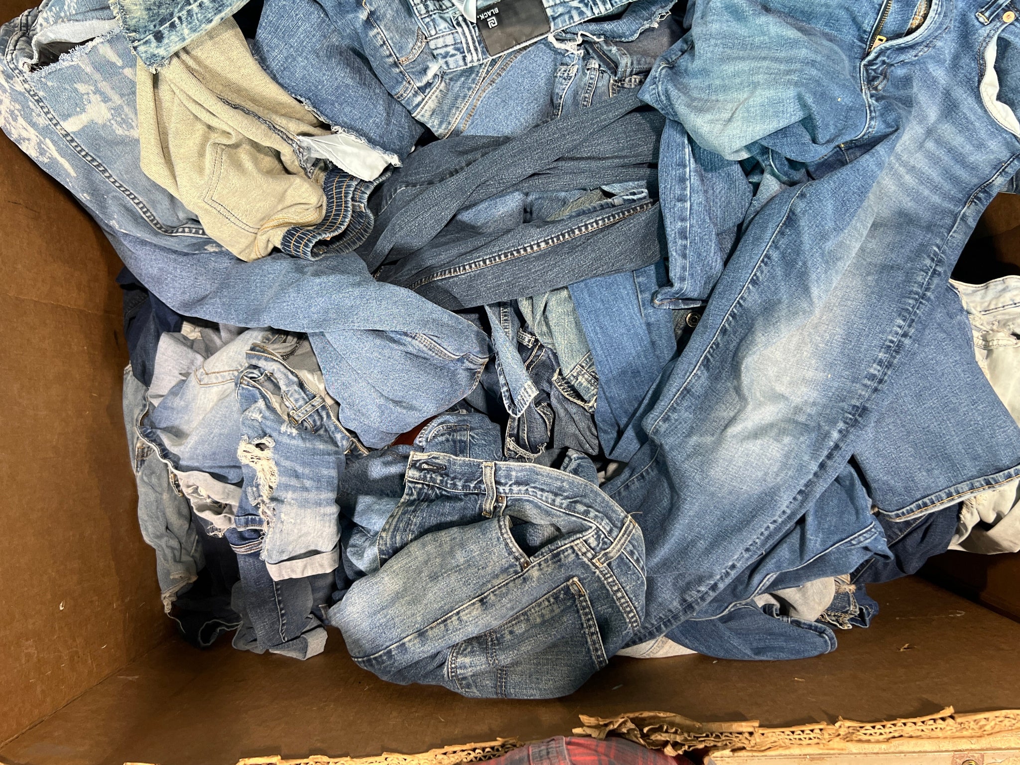 Pile of blue jeans in a cardboard box