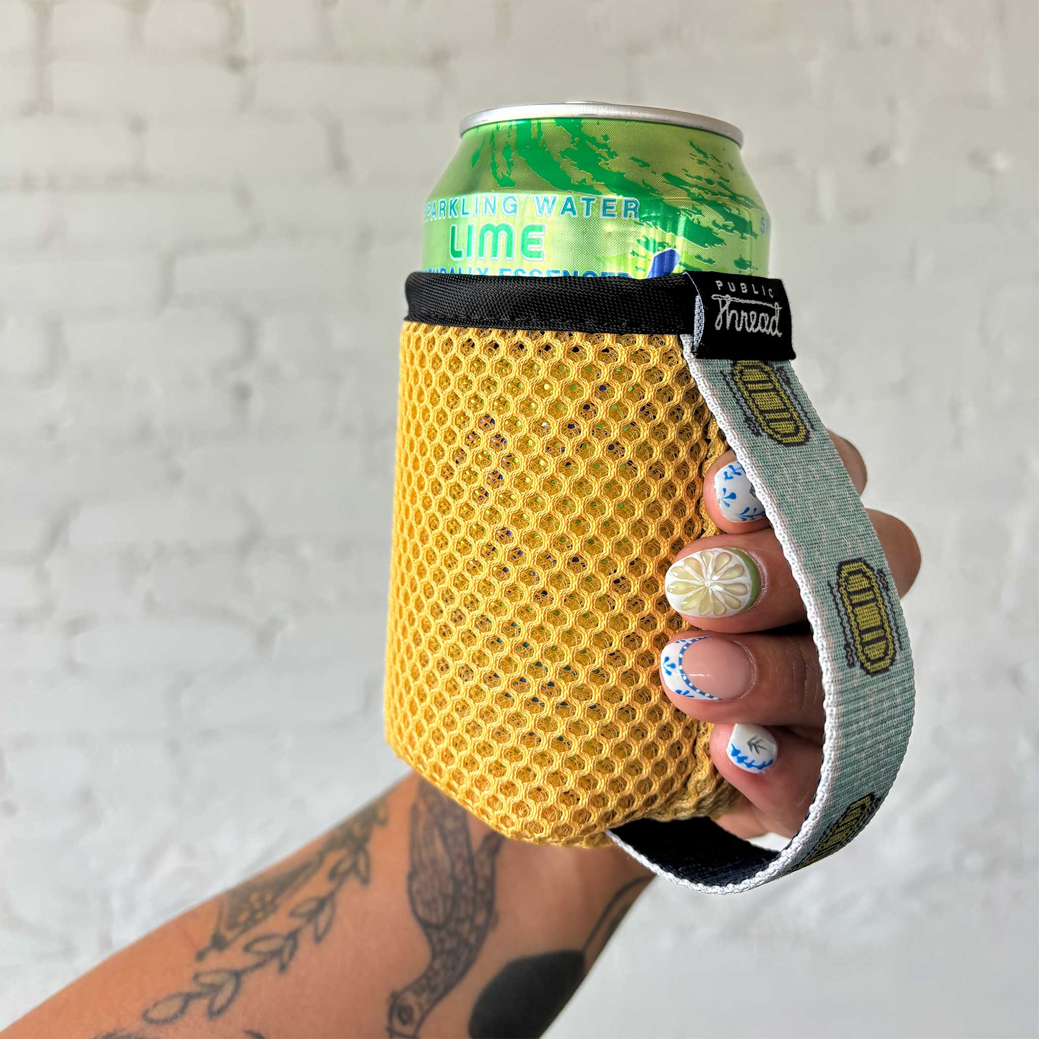Yellow koozie with a hand strap in a women's hand